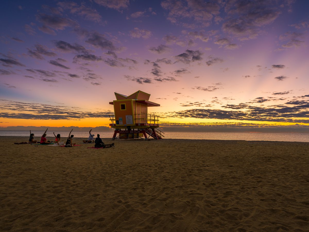 A colored lifeguard house on a Miami beach at sunrise with the ocean behind it