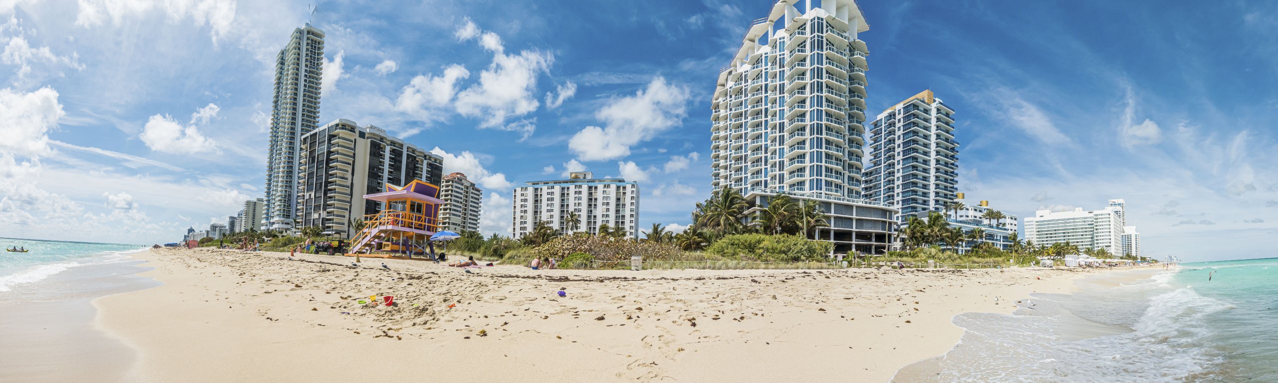 Panorama of a Miami beach with high-rises, palms, and a lifeguard house