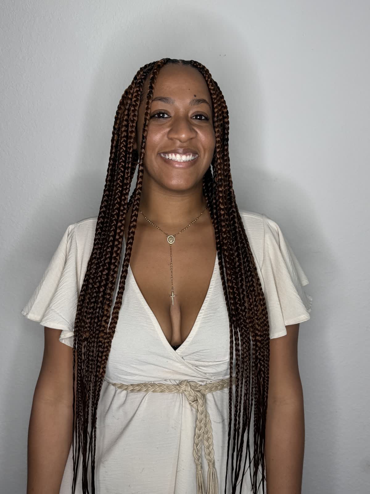 A client smiling in her long braids after an appointment at Beauty by Yulis