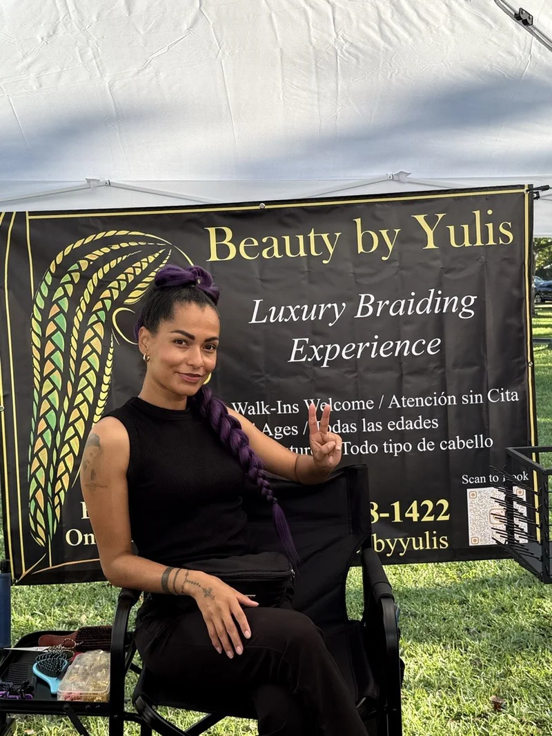 Yulis smiling in front of her Beauty By Yulis studio sign in Cutler Bay